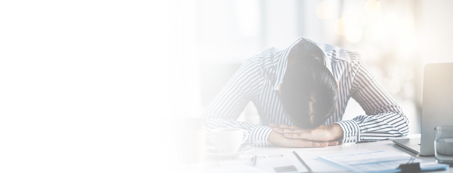 Cropped 2880x1100 left white gradient of a young businesswoman lying with her head down on a desk in an office