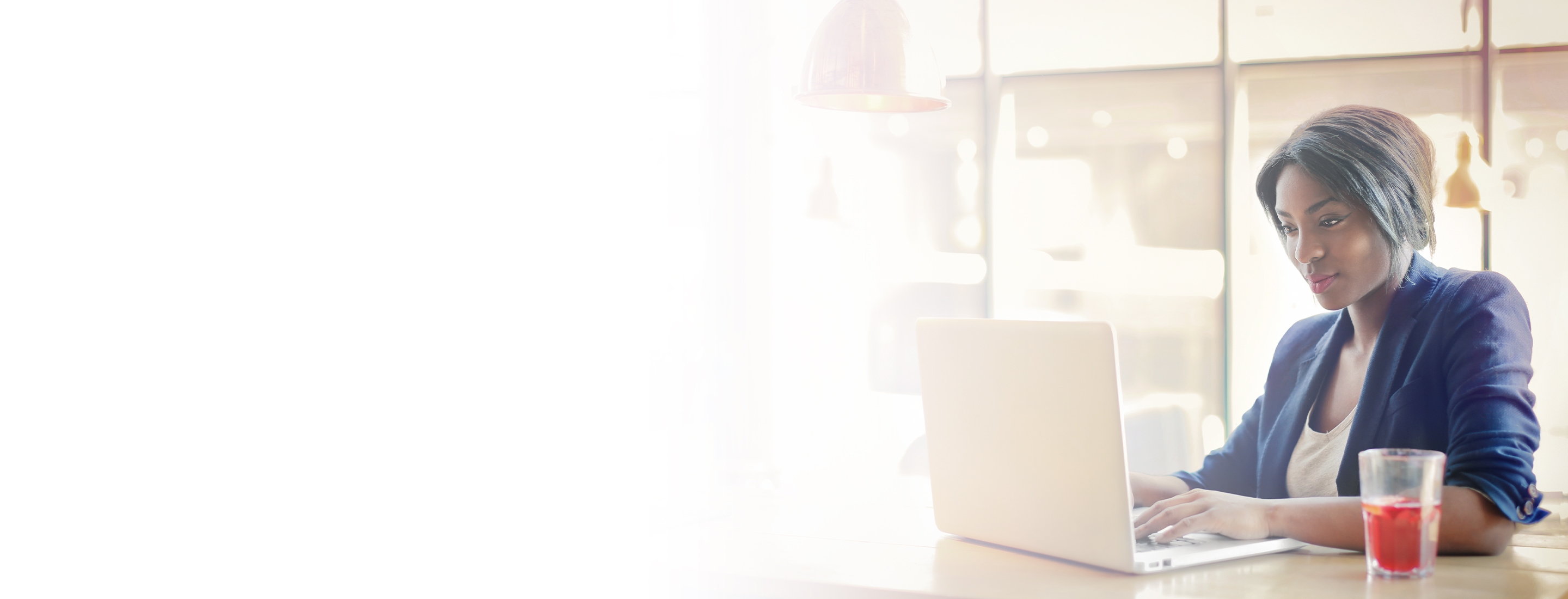 2880x1100 left white gradient of African American businesswoman working on a laptop. 