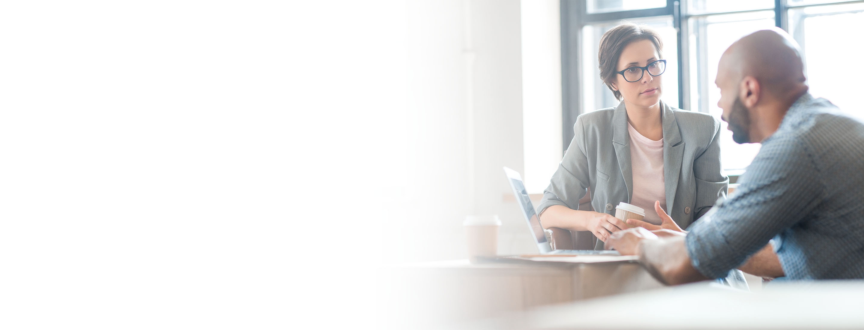 2880x1100 left white gradient of a serious woman listening to co-worker explaining new online business trends