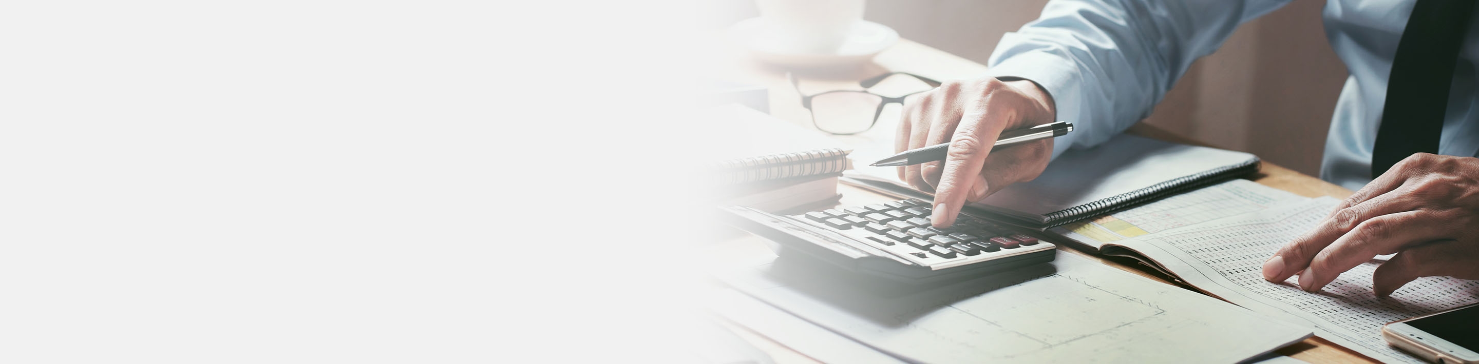 2880x710 left light gray gradient of a businessman working on desk office with using a calculator to calculate the numbers, finance accounting concept