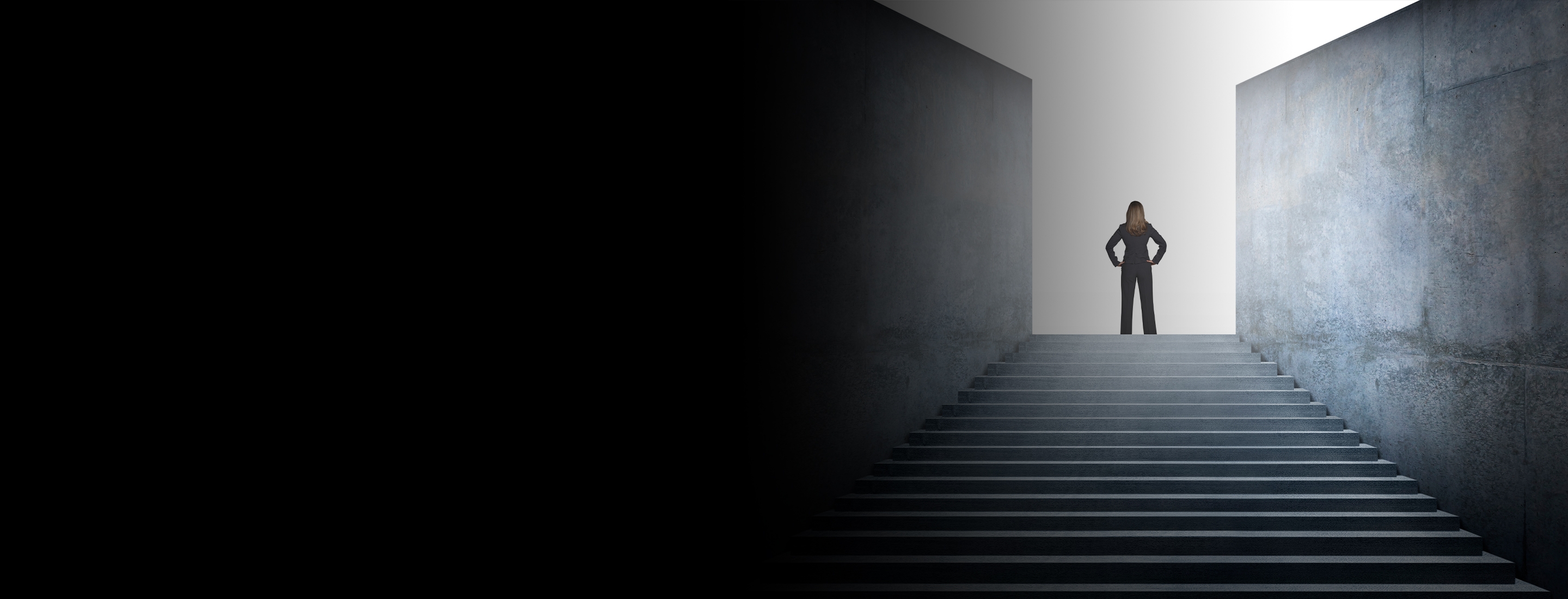 Cropped 2880x1100 left black gradient a businesswoman who has reached the top of the stairs looks out into the distance as she looks for her next challenge. 