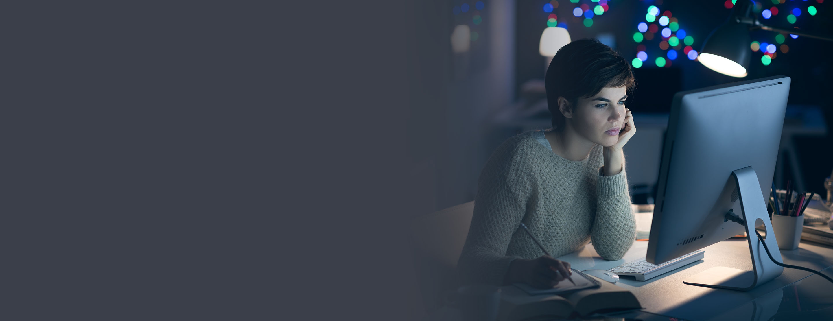 Woman, who is exempt from FLSA overtime pay,  working on her computer at night. 