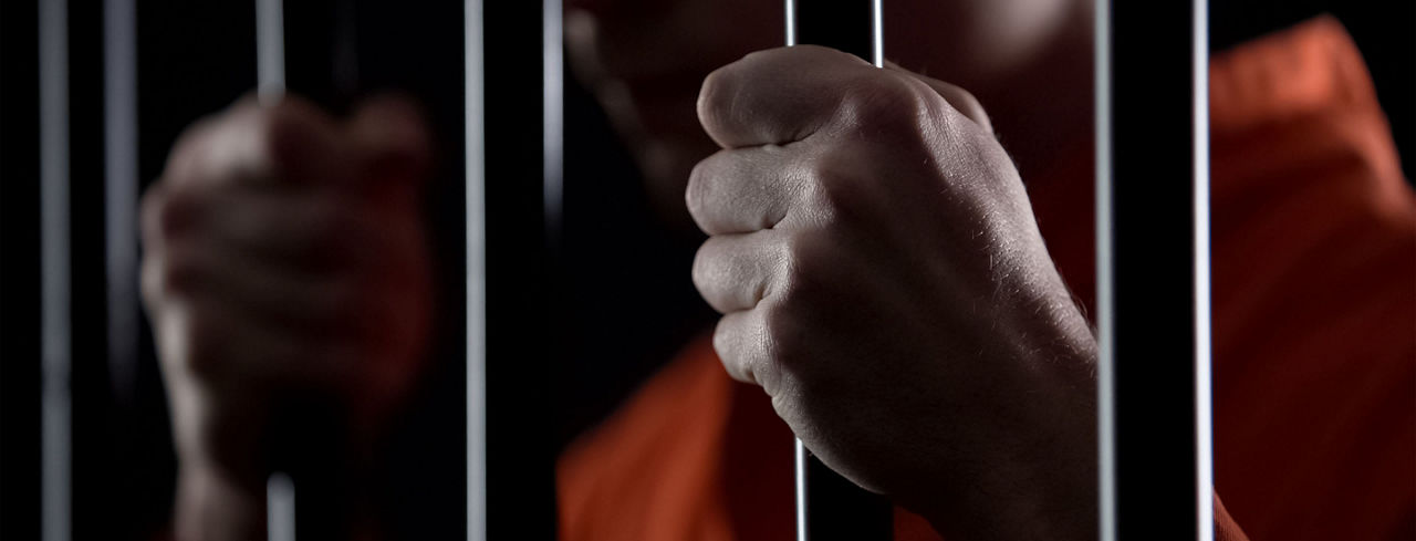 2880x1100 of a desperate criminal holding jail bars feeling regret for committing crime closeup