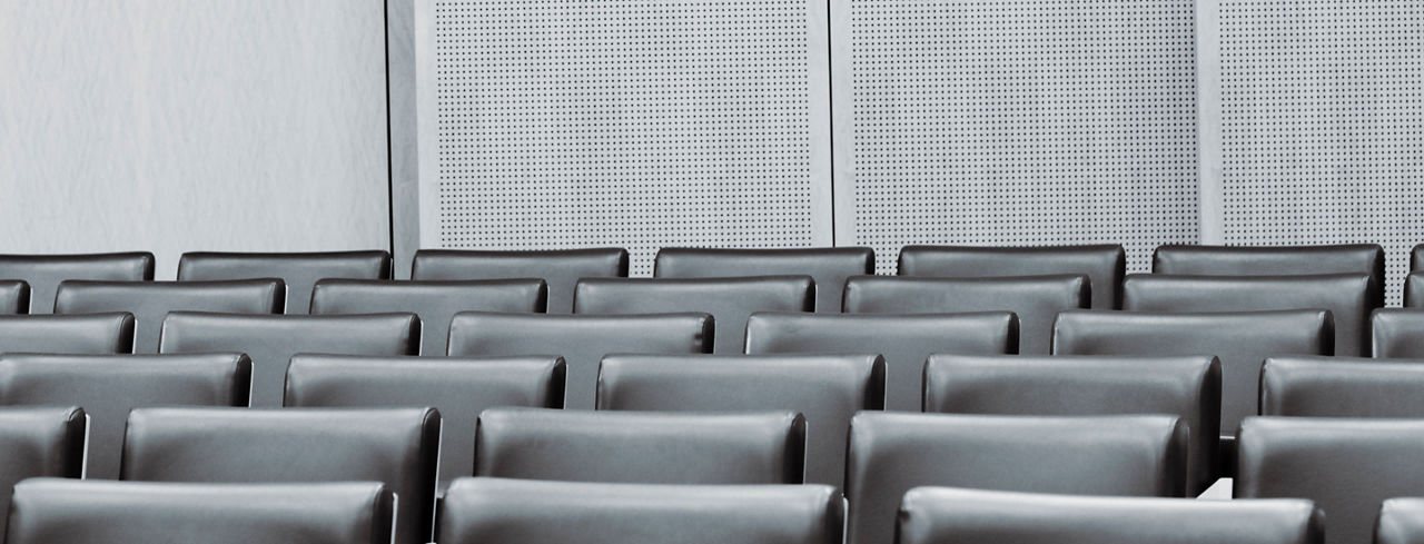 2880x1100 of empty seats in a modern courtroom. Desaturated, Toned.