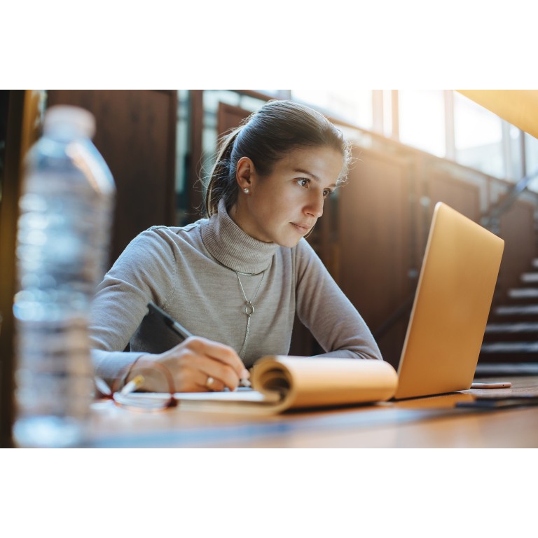 Portrait of young business woman using laptop at library
