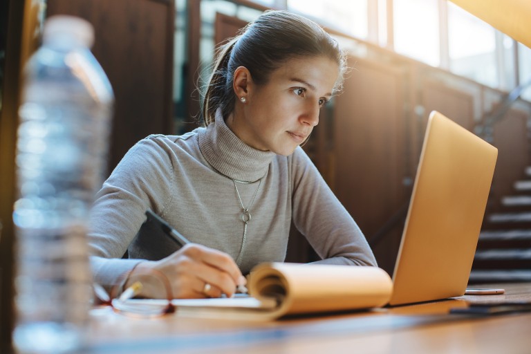 Portrait of young business woman using laptop at library
