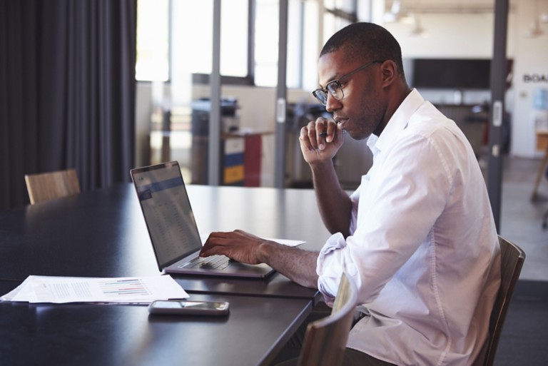 man-wearing-glasses-using-laptop-office