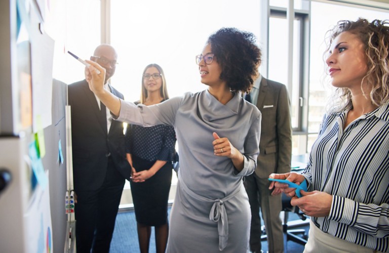 diverse-group-focused-businesspeople-brainstorming-whiteboard