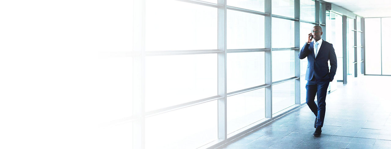 880x1100 left white gradient of an African American Business Talking to Someone on Mobile Phone While Walking at the Walkway Inside a Building