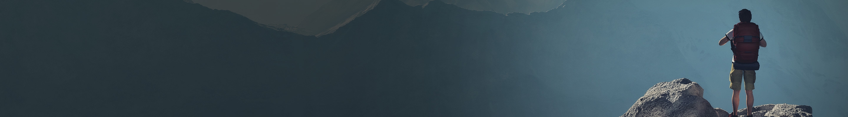Man on top of rock overlooking mountains