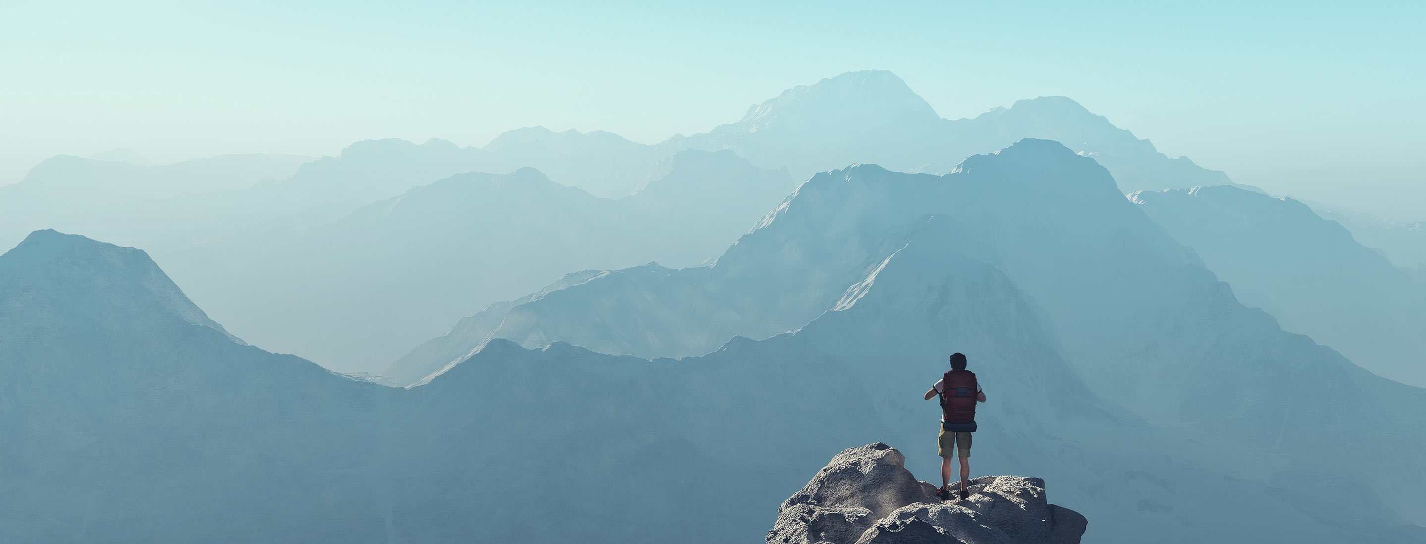 Man on top of rock overlooking mountains
