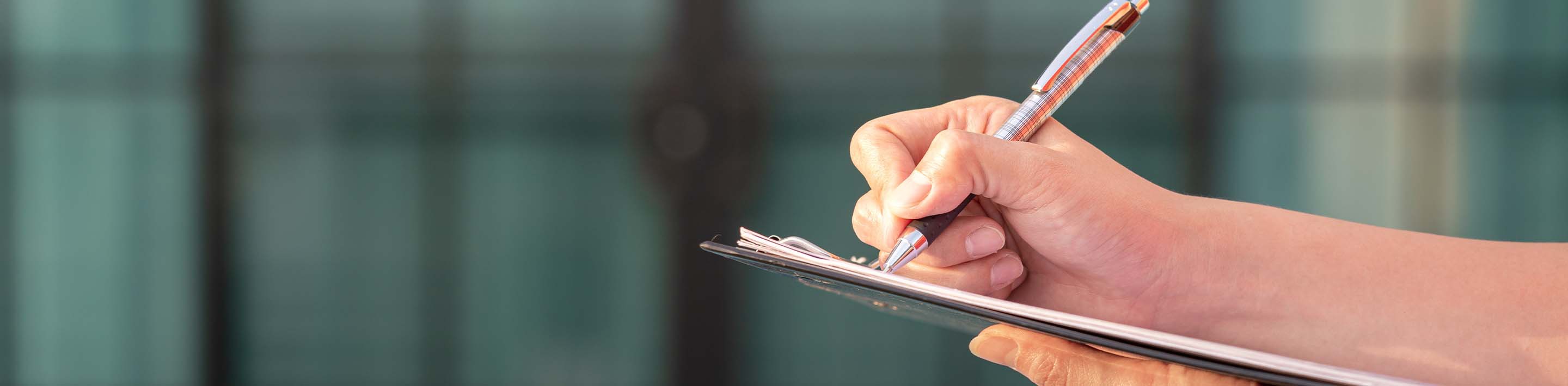 Person with pen and calculator, filling out tax forms.
