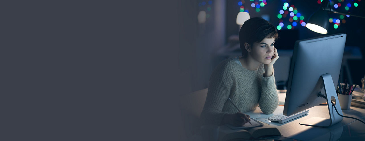 Woman, who is exempt from FLSA overtime pay,  working on her computer at night. 