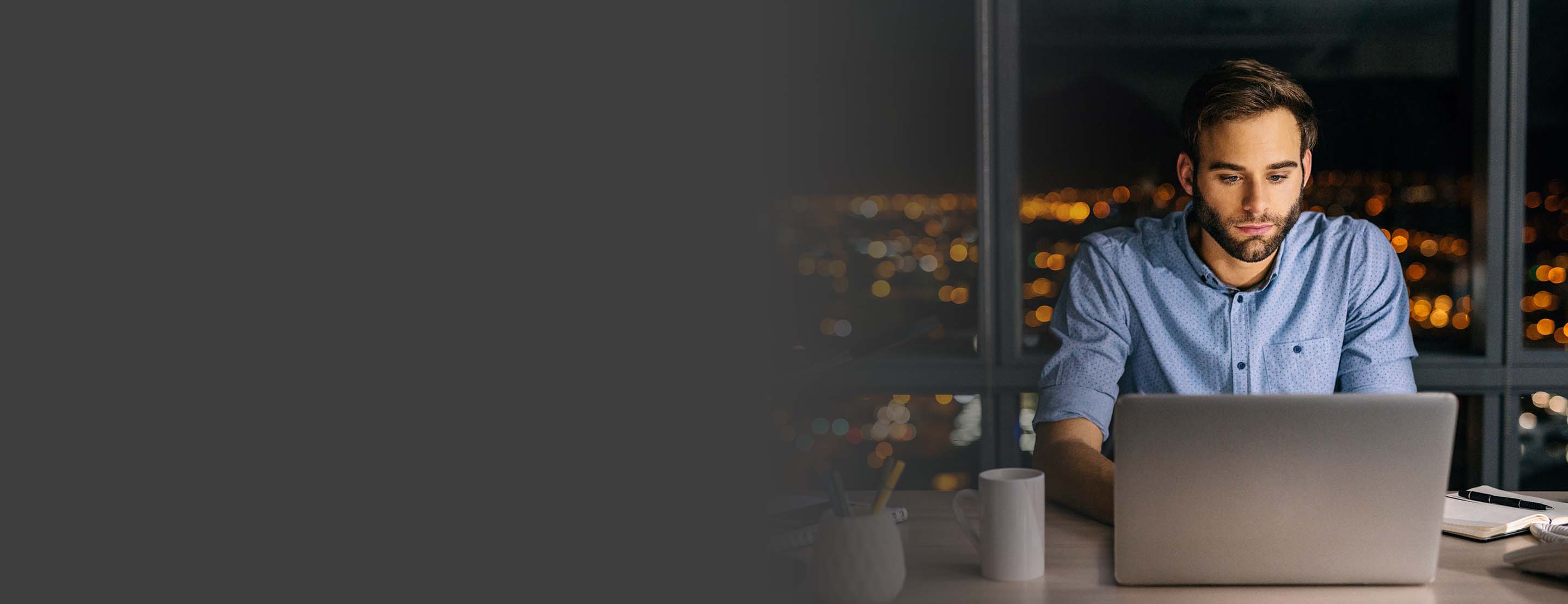 Man, who is overtime exempt under the FLSA, working on his computer at night.